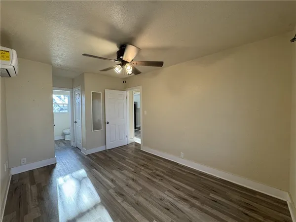 an empty room with wooden floor fan and windows