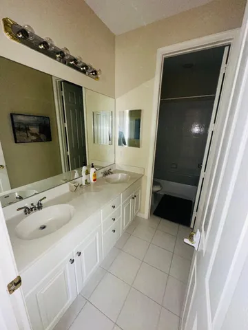 a bathroom with a double vanity sink and mirror with bathtub