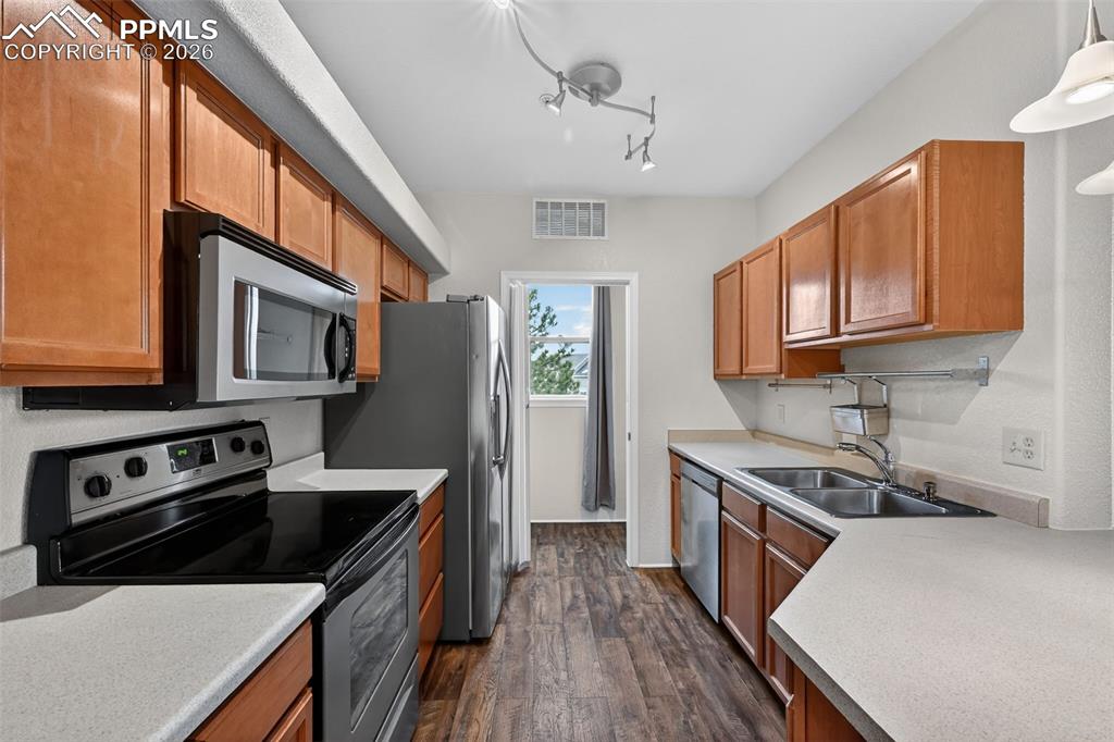 5378 Palomino Ranch Point, Unit 208 Colorado Springs, CO 80922 - Photo 21 of 38 a kitchen with stainless steel appliances granite countertop a stove a sink dishwasher a refrigerator and wooden cabinets with wooden floor