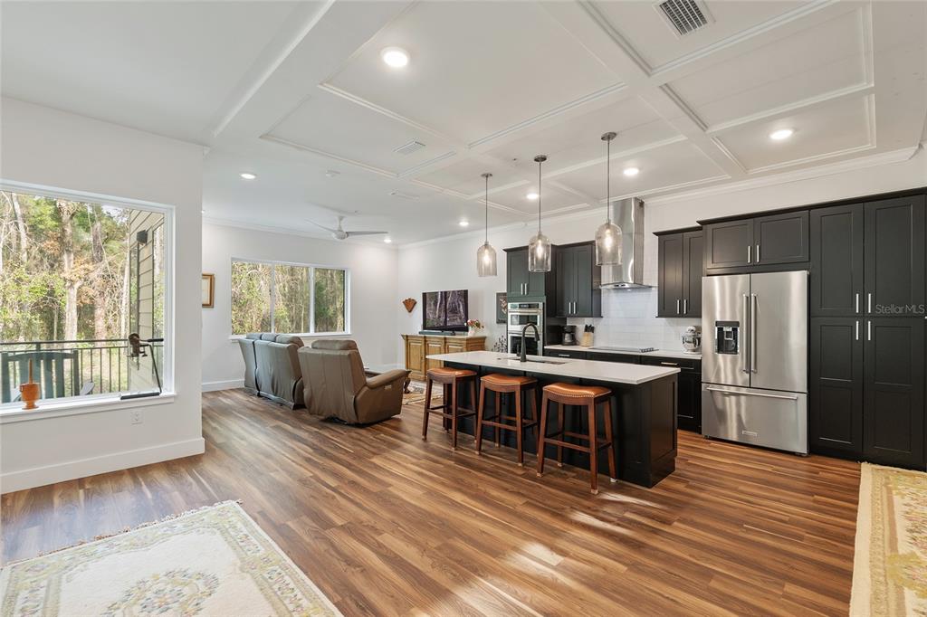 2601 Southwest Williston Road, Unit 106 Gainesville, FL 32608 - Photo 42 of 82 a large open kitchen with stainless steel appliances granite countertop a refrigerator a stove a sink a dining table and chairs with wooden floor