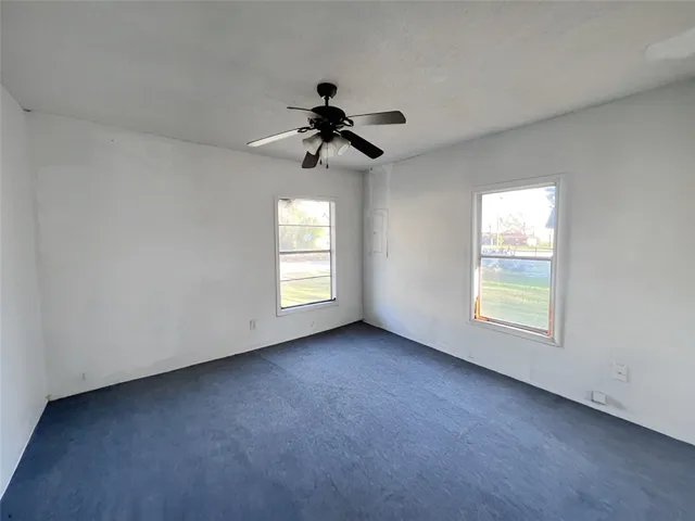 an empty room with windows and fan