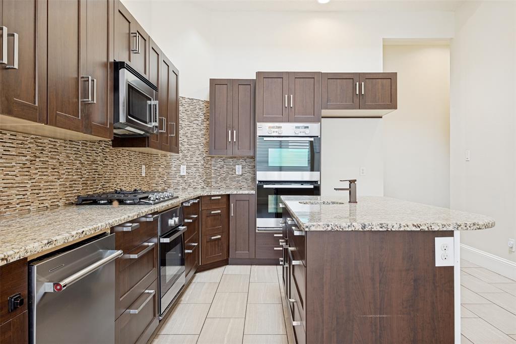 2100 Los Rios Boulevard Plano, TX 75074 - Photo 11 of 25 Modern kitchen featuring wood cabinetry, granite countertops, and a full tile backsplash