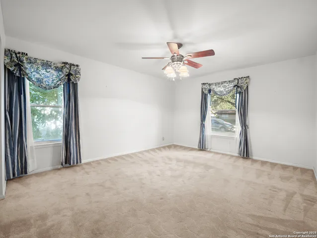a view of a big room with windows and chandelier fan