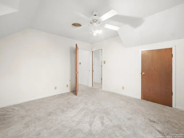 an empty room with chandelier fan and closet area
