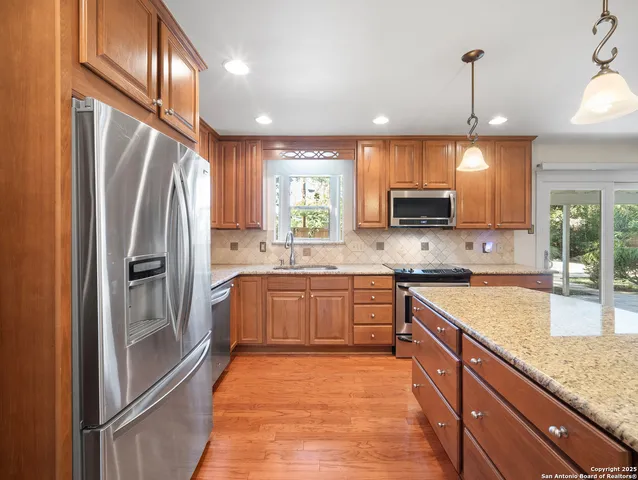 a kitchen with stainless steel appliances granite countertop a refrigerator a sink a stove and oven