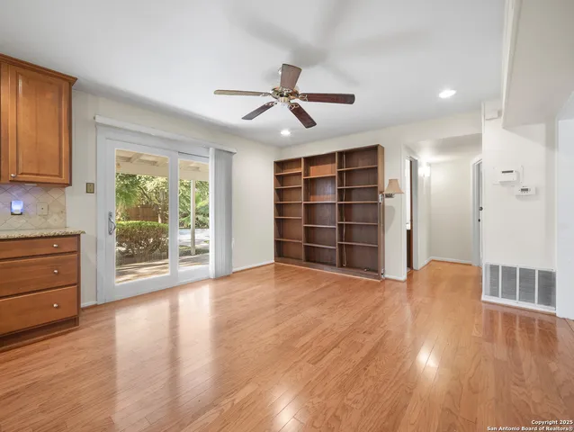 a view of an empty room with a window and wooden floor