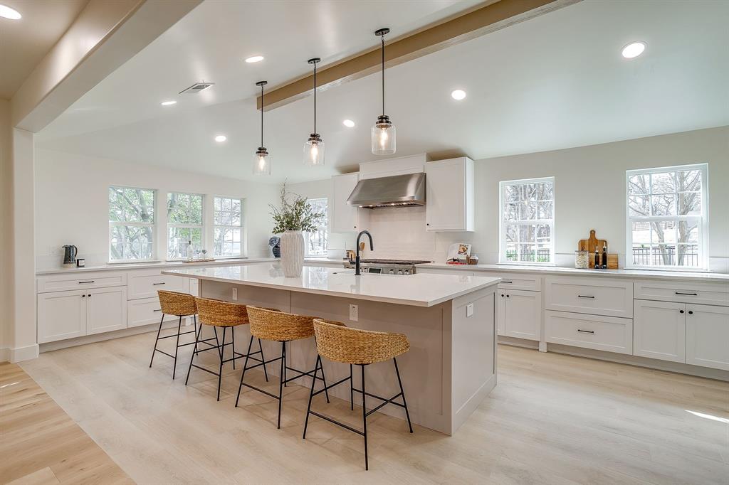 a large kitchen with kitchen island white cabinets and stainless steel appliances