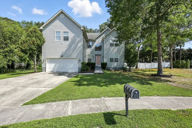 a front view of a house with a yard and trees