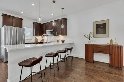 a kitchen with stainless steel appliances kitchen island granite countertop a table chairs sink and cabinets