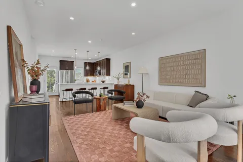 a living room with furniture wooden floor and kitchen view