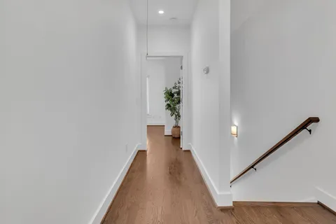 a view of a hallway with wooden floor and staircase