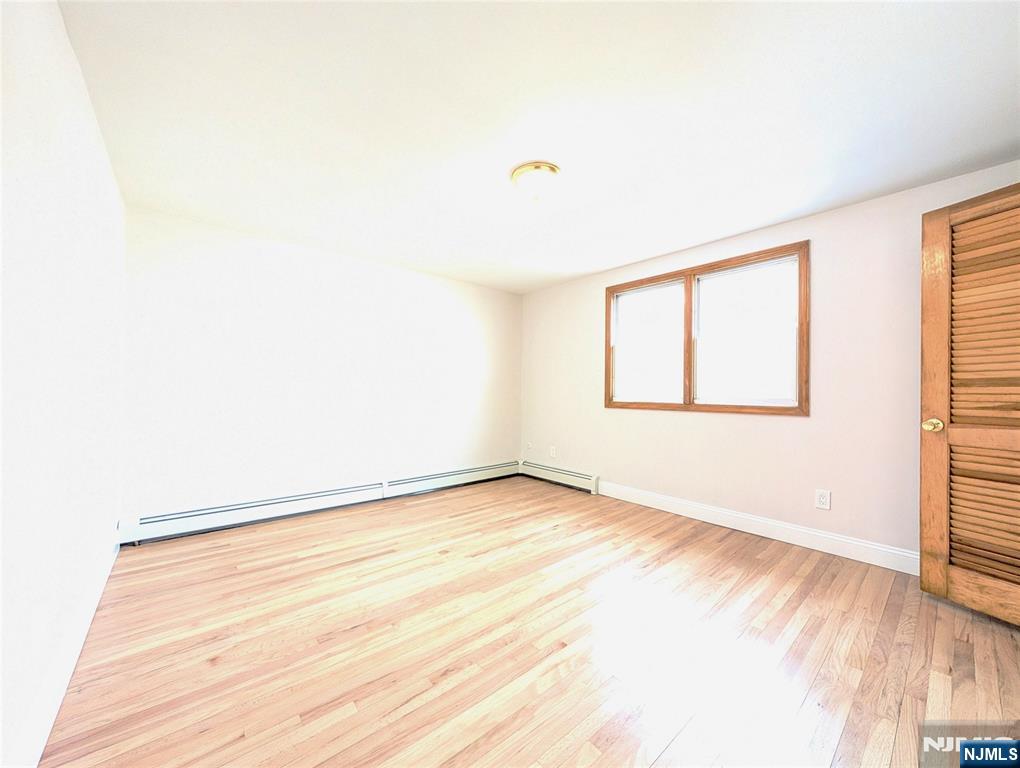 762 Cleveland Avenue, Unit 2 Harrison, NJ 07029 - Photo 13 of 14 an empty room with wooden floor and windows