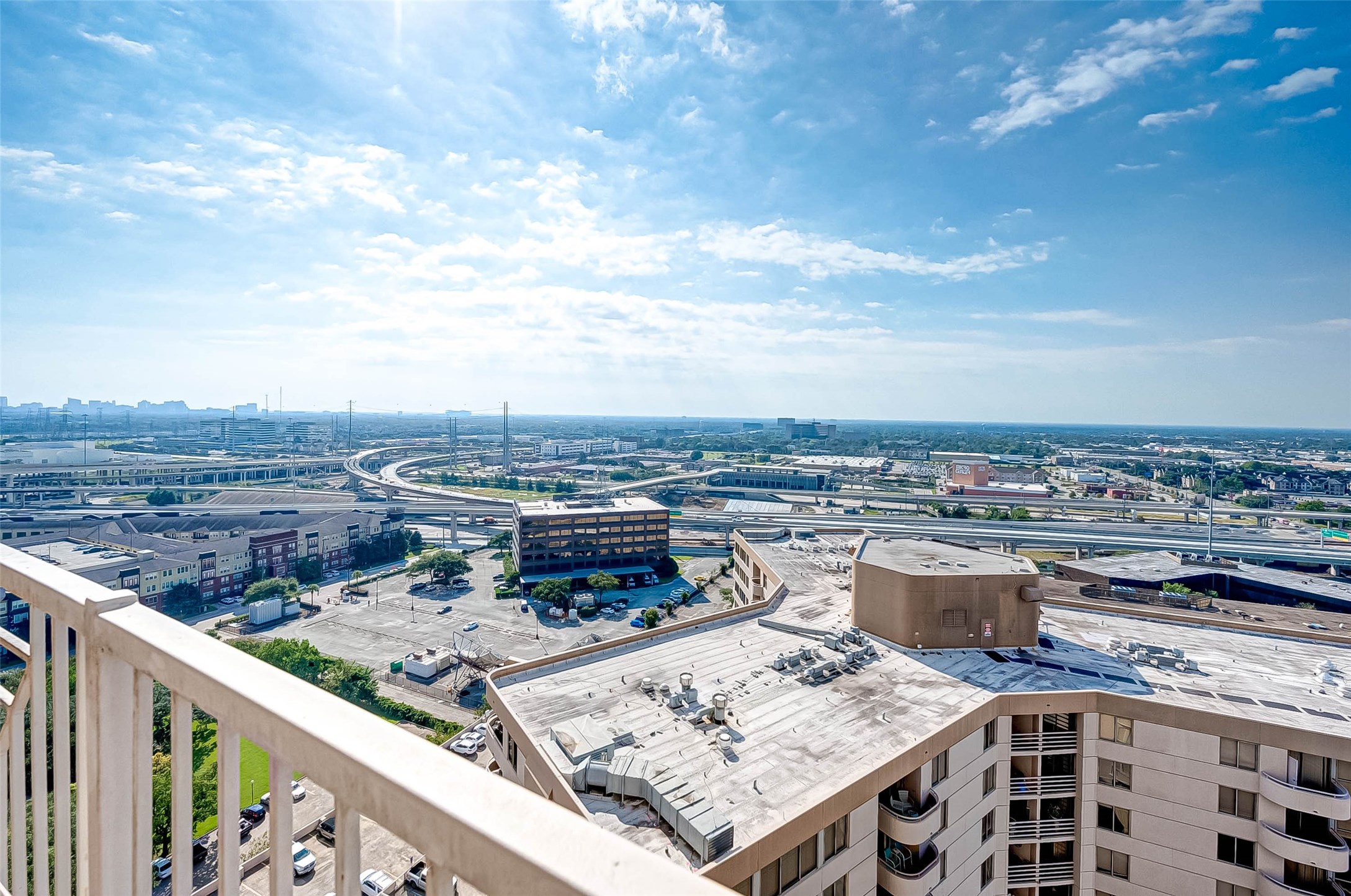 3505 Sage Road, Unit 2106 Houston, TX 77056 - Photo 23 of 31 Spacious balcony with stunning cityscape views, featuring highways and urban architecture under a bright, blue sky. Ideal for enjoying sunrise or sunset.