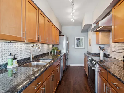 a kitchen with stainless steel appliances a sink dishwasher a stove a refrigerator with wooden cabinets and floor