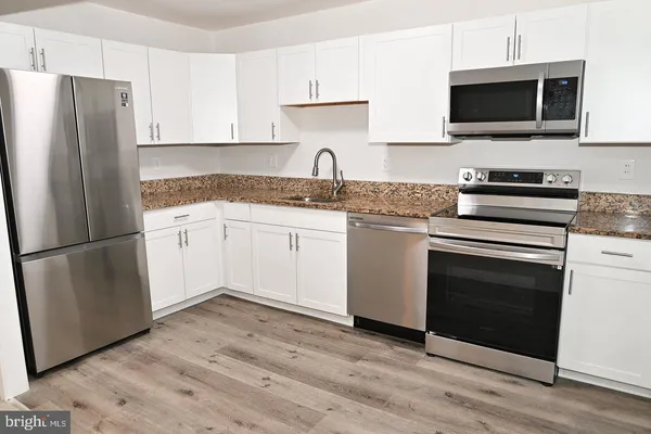 a kitchen with stainless steel appliances a stove microwave and sink