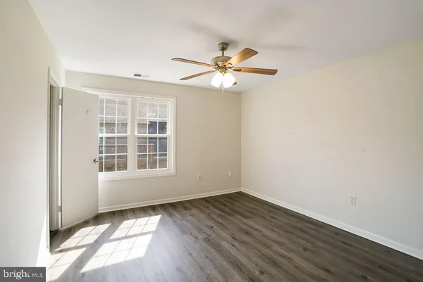 an empty room with wooden floor chandelier fan and windows