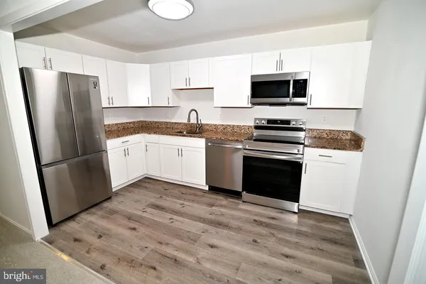 a kitchen with granite countertop a refrigerator stove and microwave