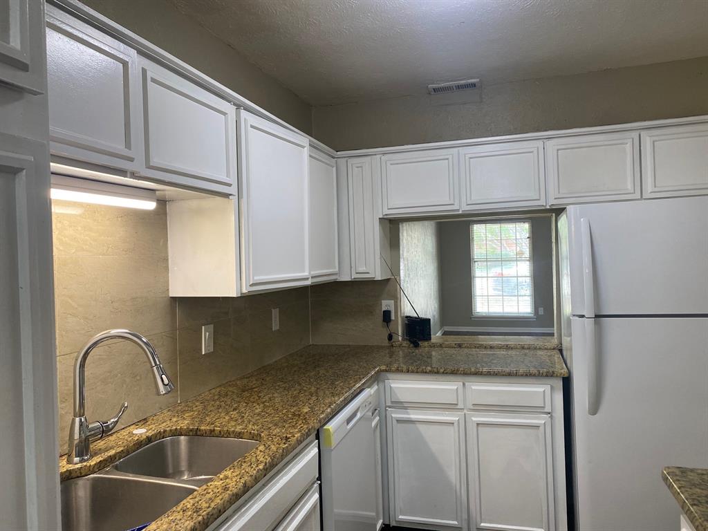 13652 Flagstone Lane Dallas, TX 75240 - Photo 5 of 15 Kitchen featuring white appliances, decorative backsplash, white cabinetry, dark stone countertops, and a textured ceiling