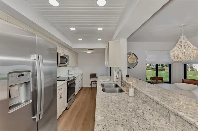 a kitchen with stainless steel appliances granite countertop a stove a sink and a white cabinets