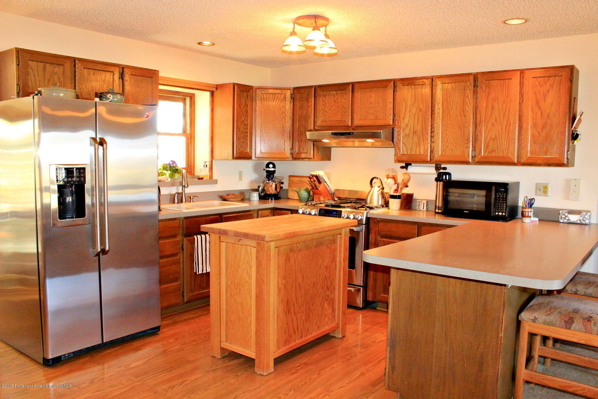 1018 County Road 294 Rifle, CO 81650 - Photo 5 of 31 a kitchen with stainless steel appliances a refrigerator a sink dishwasher a stove top oven a dining table and chairs with wooden floor