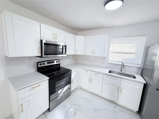 a kitchen with white cabinets appliances and sink