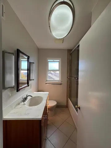 a bathroom with a granite countertop sink a mirror and a toilet