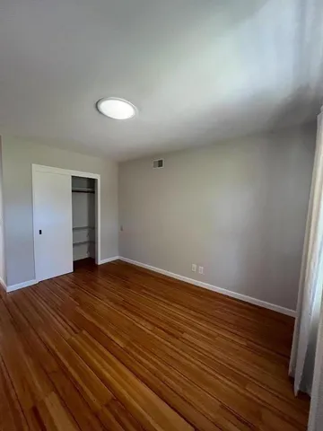 a view of an empty room with wooden floor and cabinet