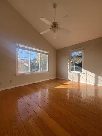 a view of an empty room with window and wooden floor