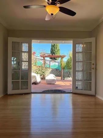 a view of empty room with wooden floor and fan
