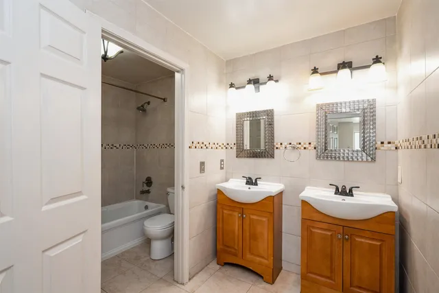 a bathroom with a double vanity sink toilet mirror and shower