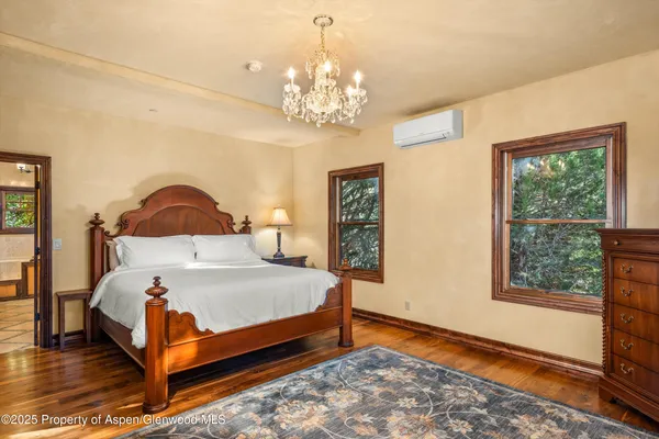 a bedroom with a bed chandelier and a window