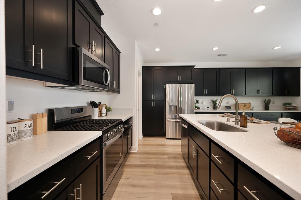 17500 Beachwood Road Lathrop, CA 95330 - Photo 21 of 78 a kitchen with stainless steel appliances a sink dishwasher a stove top oven a refrigerator with wooden cabinets and cabinets