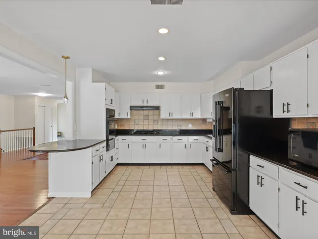 a large kitchen with stainless steel appliances and white cabinets