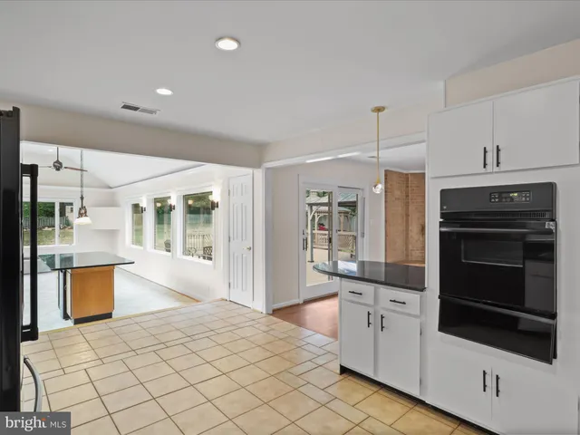 a kitchen with stainless steel appliances kitchen island granite countertop a refrigerator oven a sink dishwasher and white cabinets with wooden floor