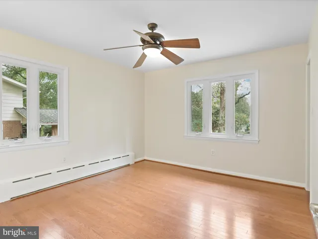 a view of a room with wooden floor ceiling fan and window