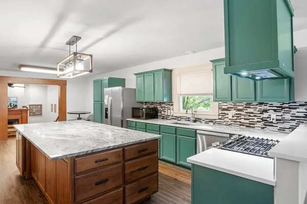 a kitchen with kitchen island a sink stove and refrigerator