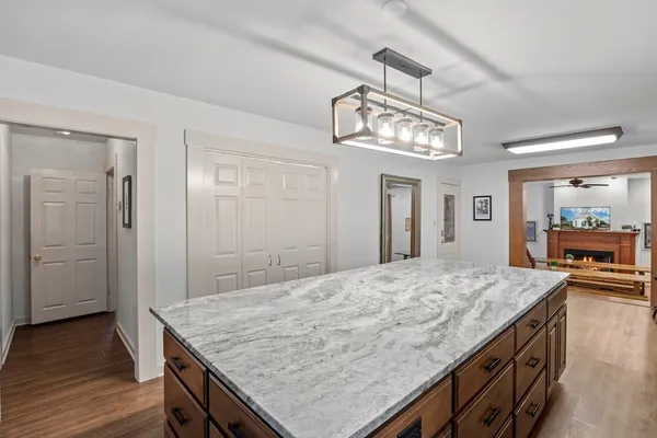 a room with kitchen island a chandelier and wooden floor
