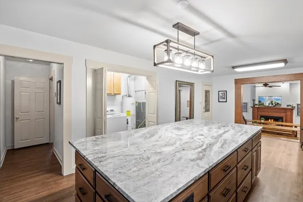 a room with kitchen island a chandelier and wooden floor