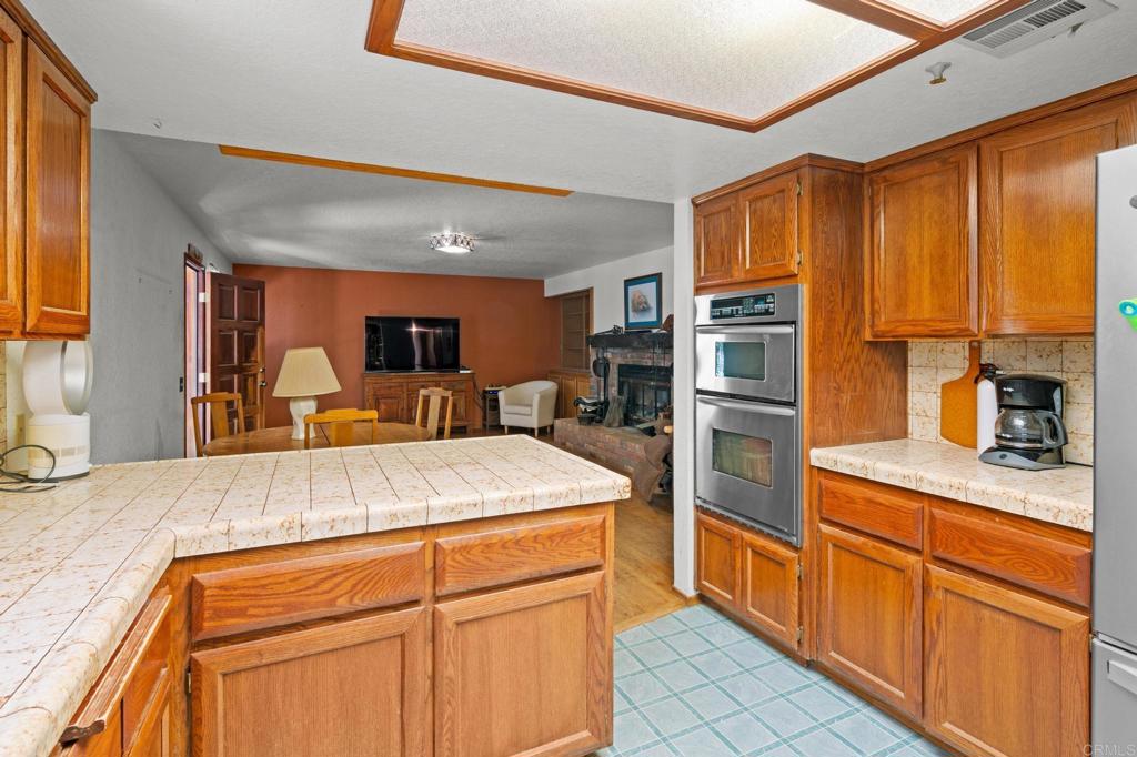 5041 Pine Ridge Avenue Julian, CA 92036 - Photo 13 of 27 a kitchen with stainless steel appliances kitchen island granite countertop a refrigerator oven a sink dishwasher and white cabinets with wooden floor