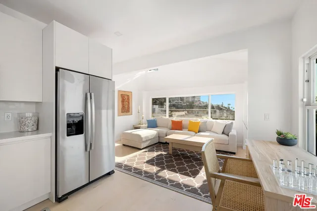 a living room with furniture large windows and wooden floor