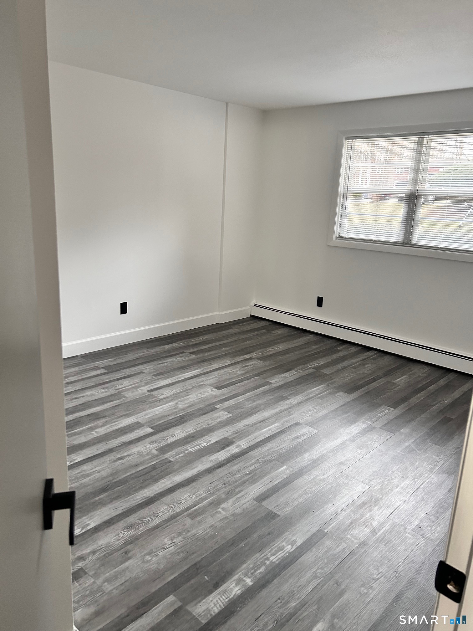 1109 Waterbury Road, Unit 1A Cheshire, CT 06410 - Photo 6 of 15 a view of an empty room with wooden floor and a window