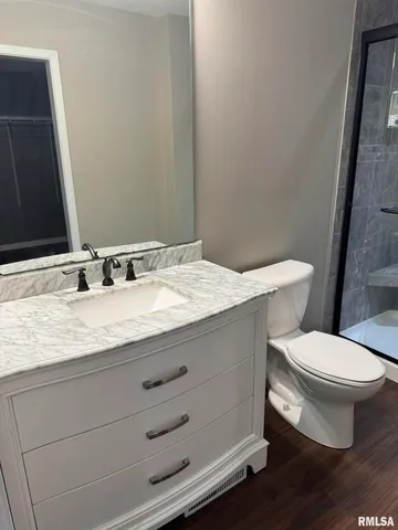 a bathroom with a granite countertop toilet sink and mirror