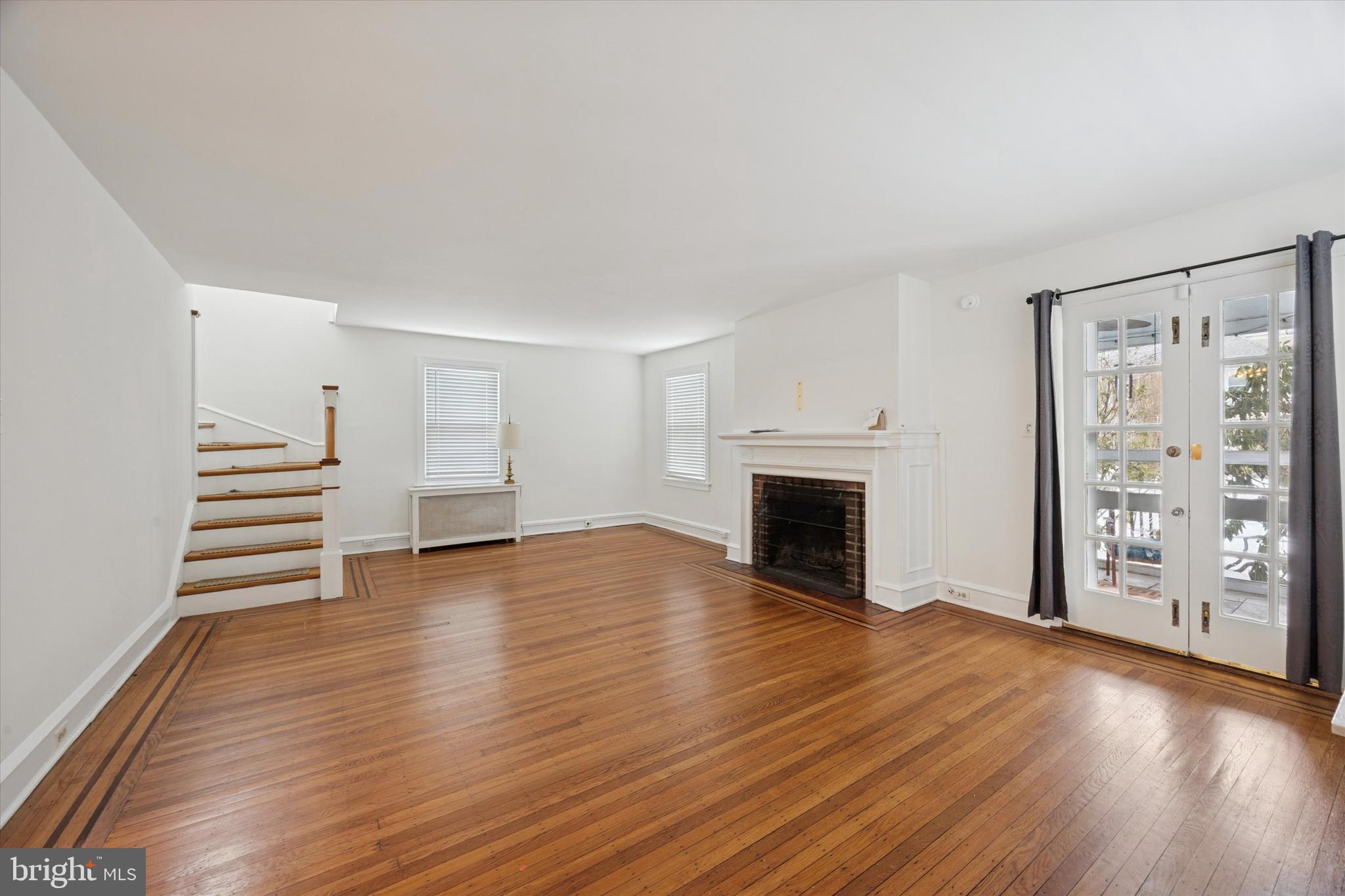 74 Drexel Avenue Lansdowne, PA 19050 - Photo 4 of 15 an empty room with wooden floor fireplace and windows