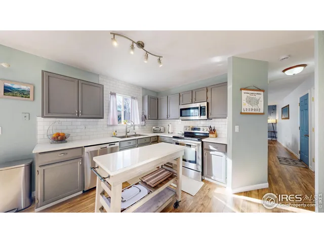 a kitchen with stainless steel appliances kitchen island granite countertop a refrigerator oven a sink a dining table and chairs with wooden floor