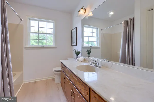 a bathroom with a granite countertop sink a toilet a large mirror and a window