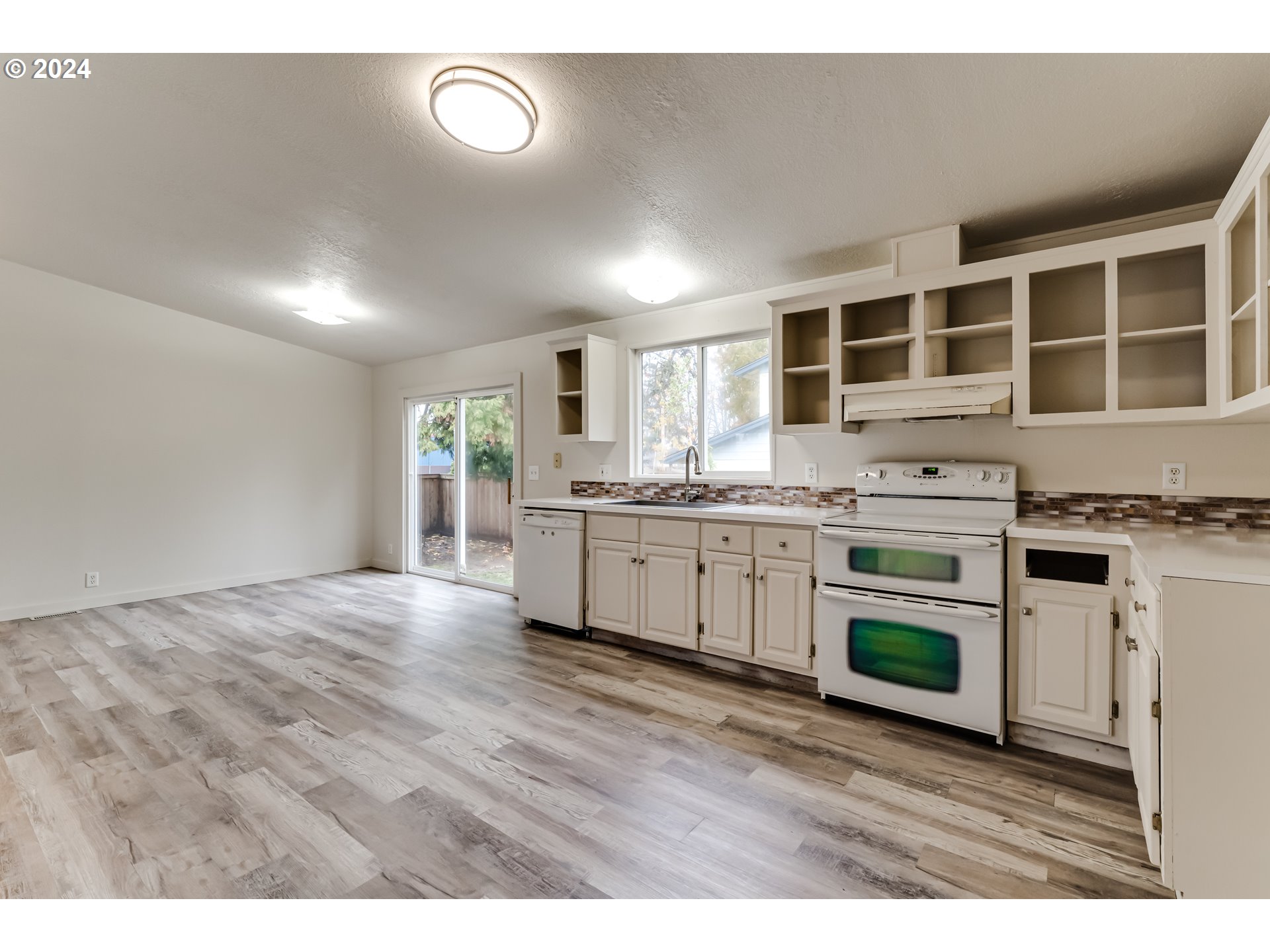 301 Smith Loop Springfield, OR 97478 - Photo 10 of 32 a kitchen with stainless steel appliances granite countertop a stove top oven a sink dishwasher and white cabinets with wooden floor