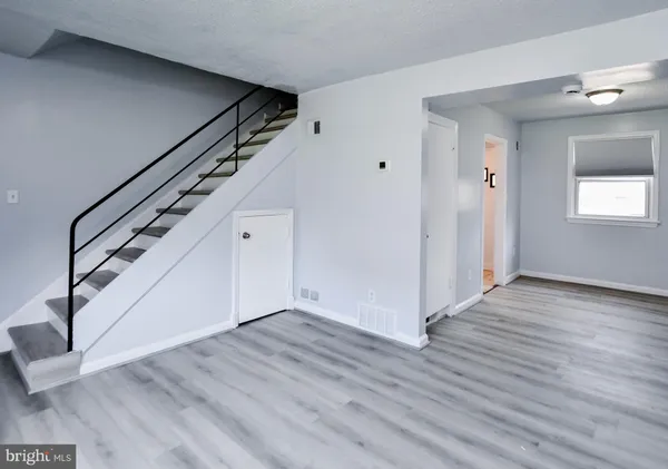 a view of an empty room with wooden floor and stairs
