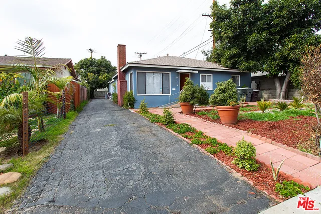 a front view of a house with a yard and potted plants