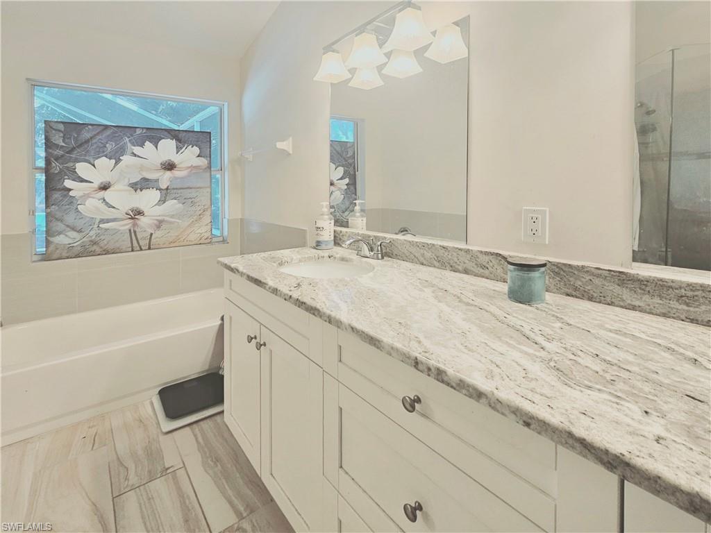 6708 Sloane Place Naples, FL 34104 - Photo 17 of 31 a spacious bathroom with a granite countertop sink a mirror a vanity and bathtub