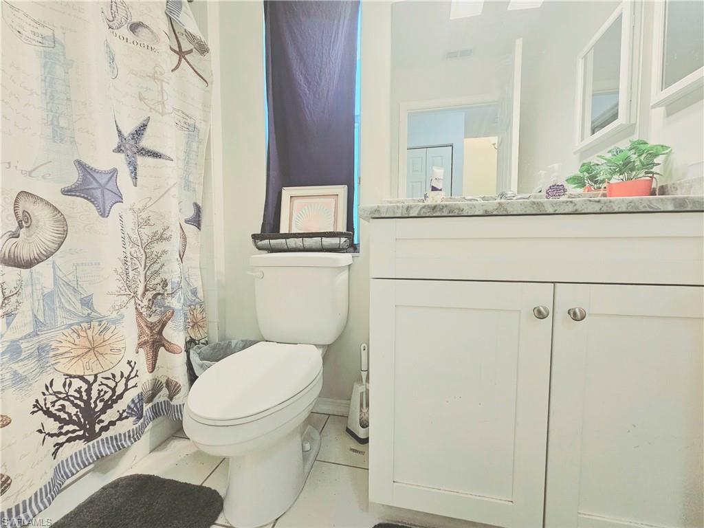 6708 Sloane Place Naples, FL 34104 - Photo 19 of 31 a bathroom with a granite countertop toilet sink and mirror